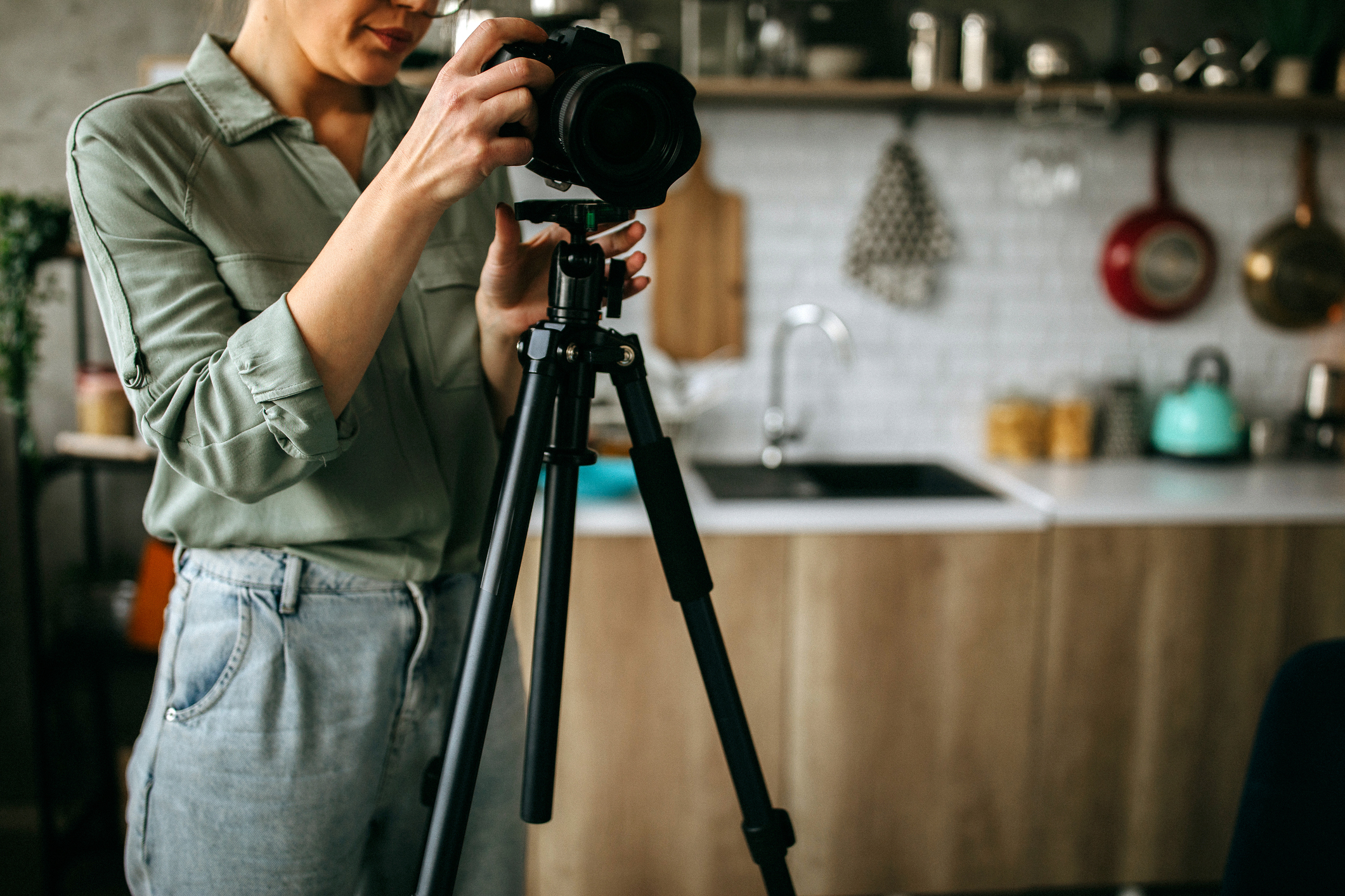 Female photographer with camera on tripod getting ready for photo shoot inside a house.