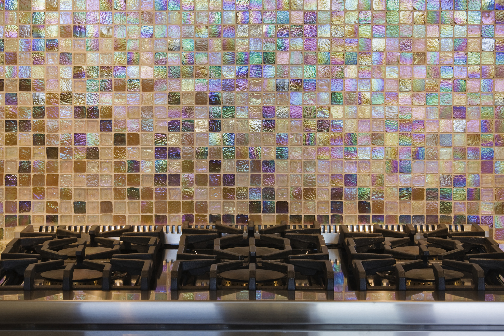 Iridescent kitchen backsplash with small pink, green, and tan tiles.