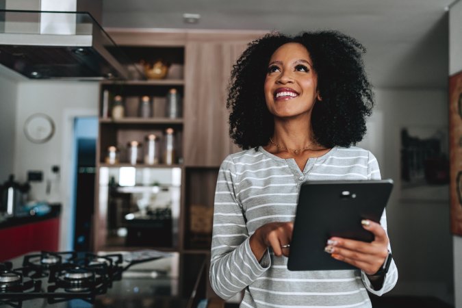 Woman standing in a kitchen controlling her smart home using an automated system