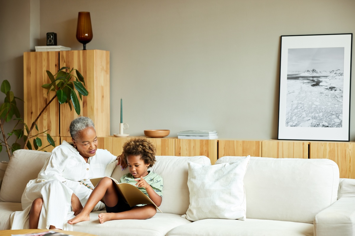 A senior woman reading with her grandson in a minimalistic living room.