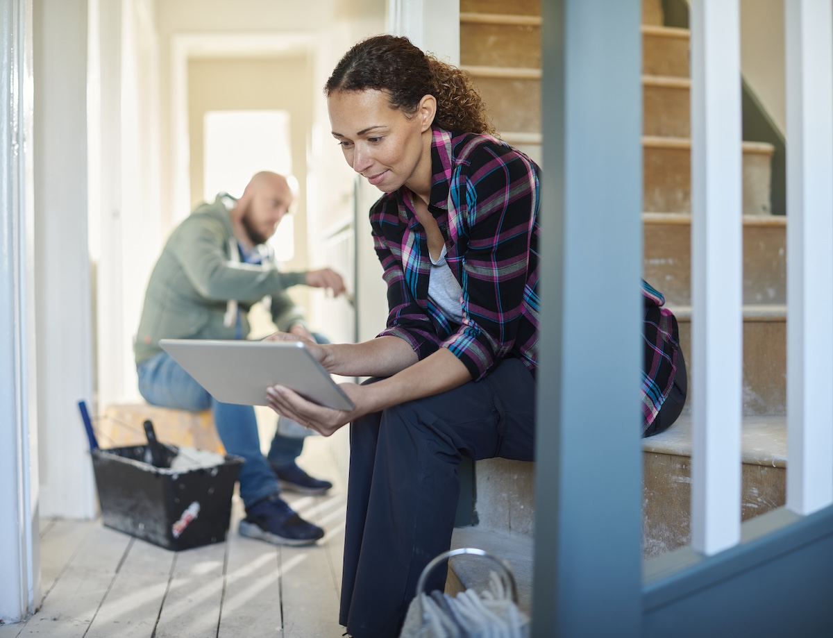 A woman uses a computer while sitting in her home that is mid-renovation.