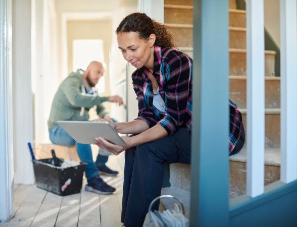 A woman uses a computer while sitting in her home that is mid-renovation.