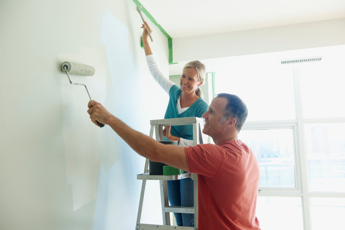 Smiling woman and man painting an interior wall.