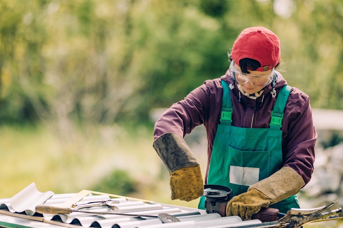 A DIYer using an angle grinder to cut metal for a raised garden bed.