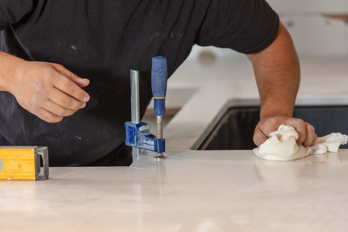 A contractor installing a white quartz countertop in a minor kitchen remodel.