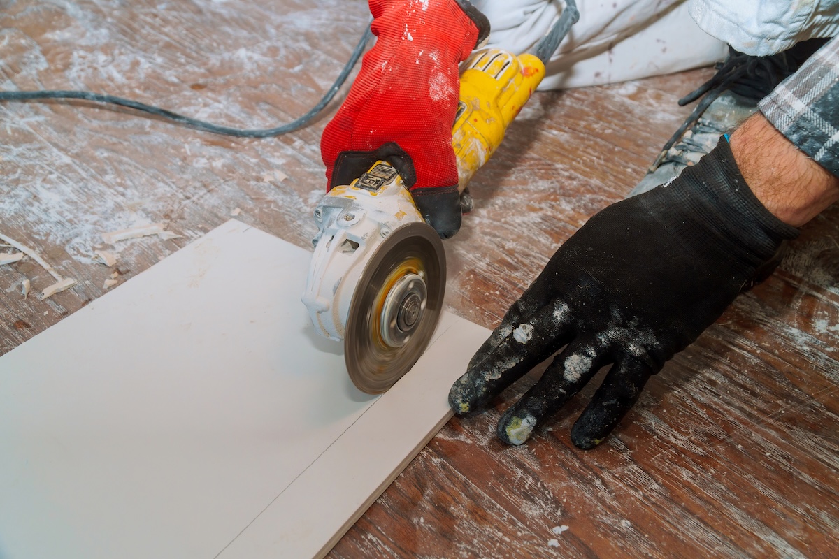 A DIYer using an angle grinder to cut tile.