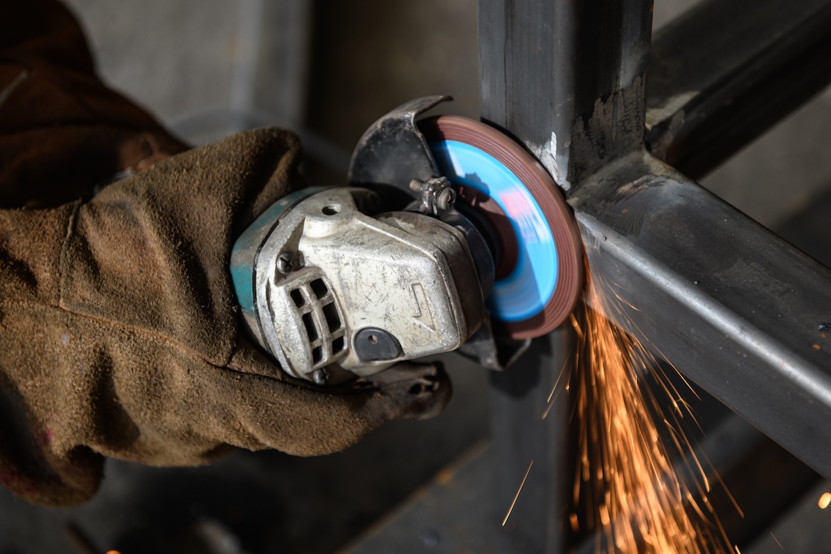 A person using an angle grinder to grind metal.
