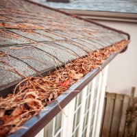 House gutter clogged with leaves, twigs, and other debris