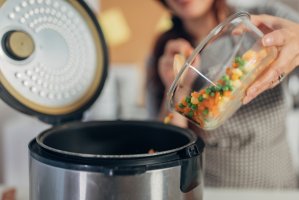 Woman using slow cooker while preparing food in the kitchen