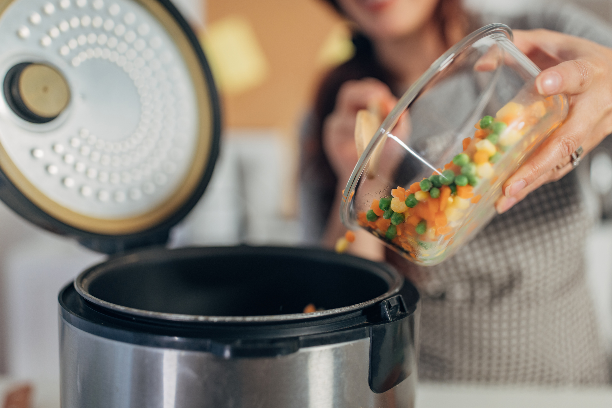Woman using slow cooker while preparing food in the kitchen