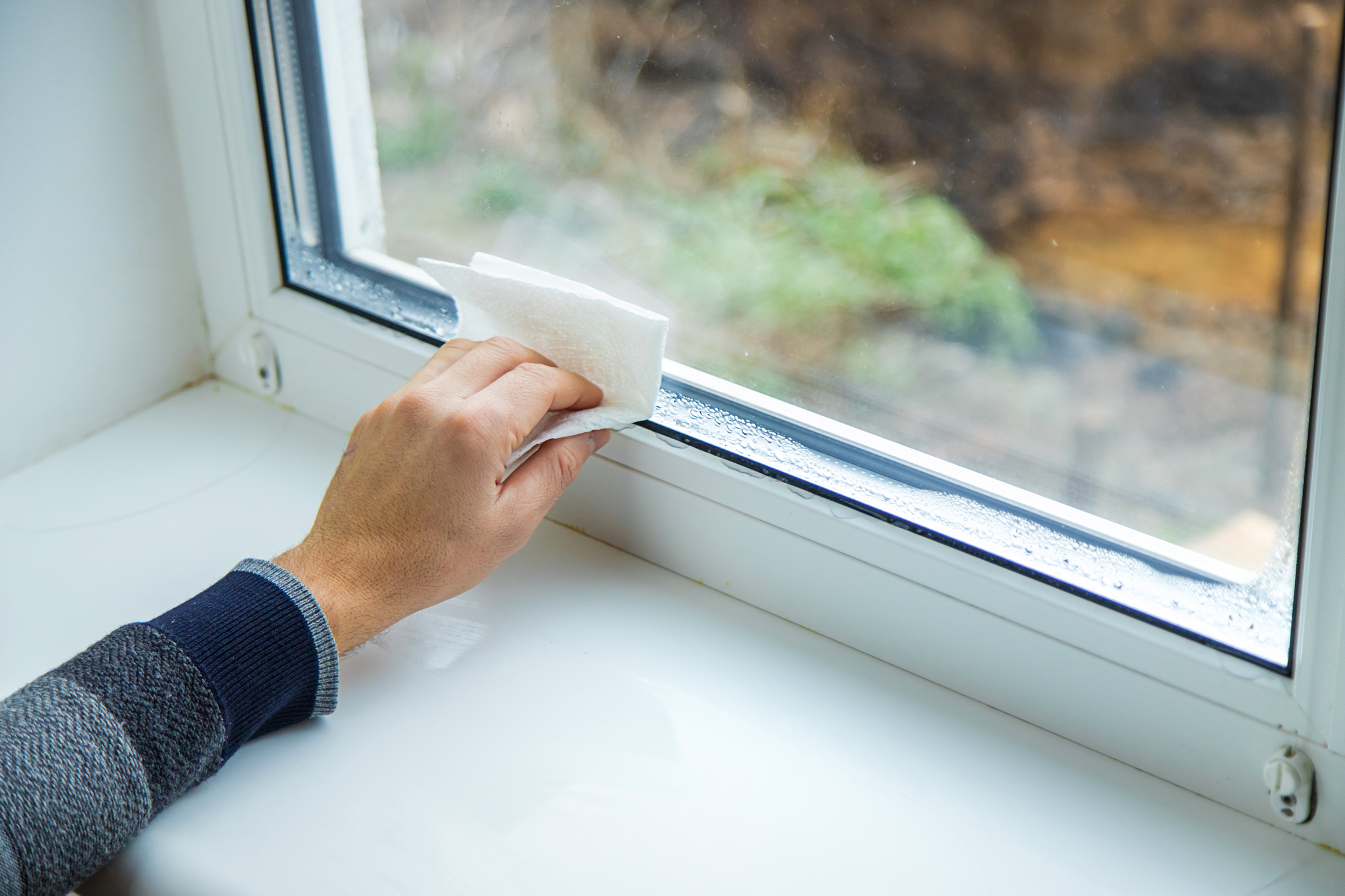 Cropped hand cleaning moisture on a window.
