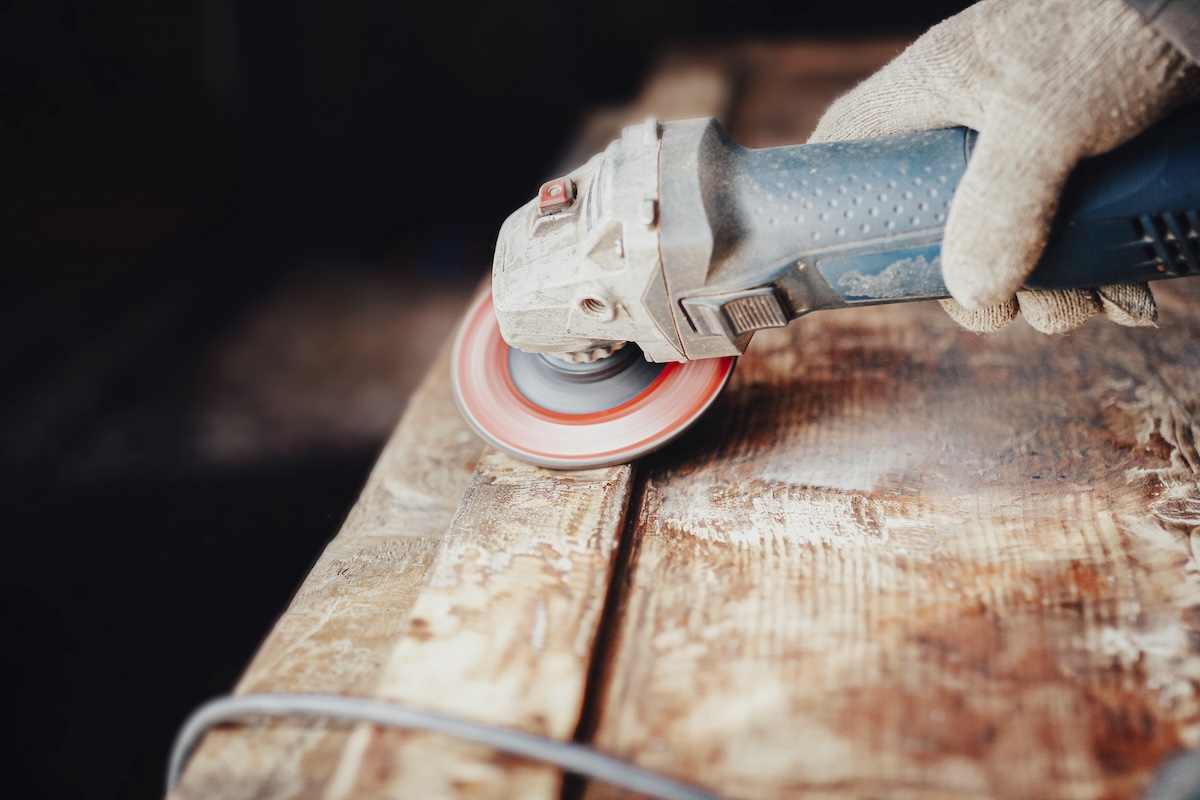 A DIYer using an angle grinder for sanding.