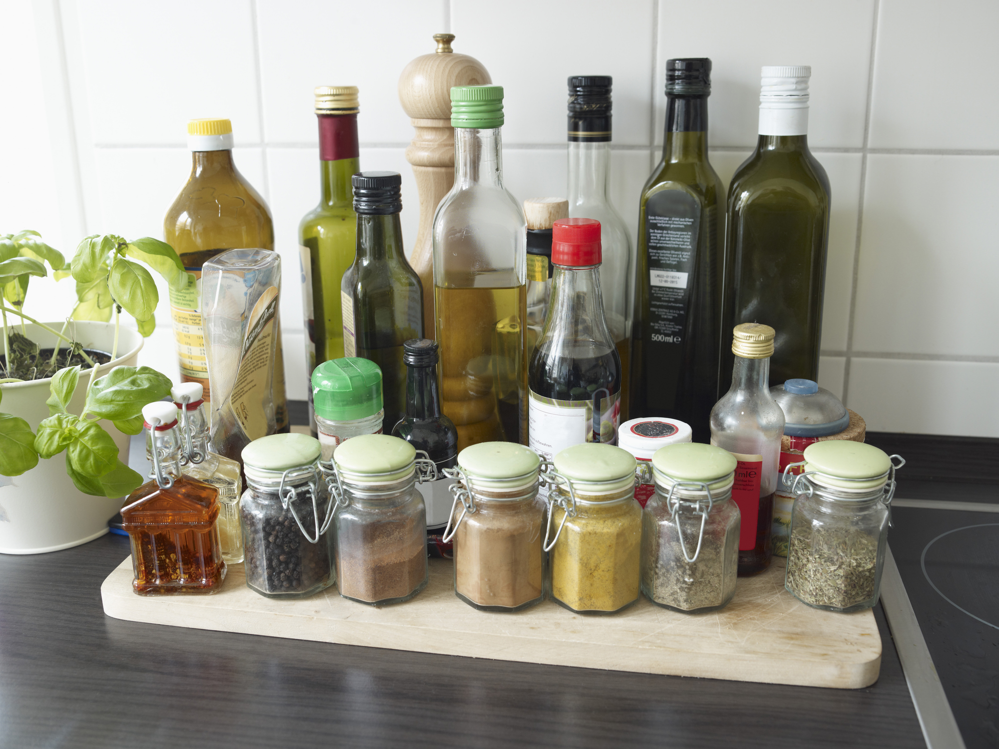 Bottles of vinegar, oils, and spices on the counter next to a stove.