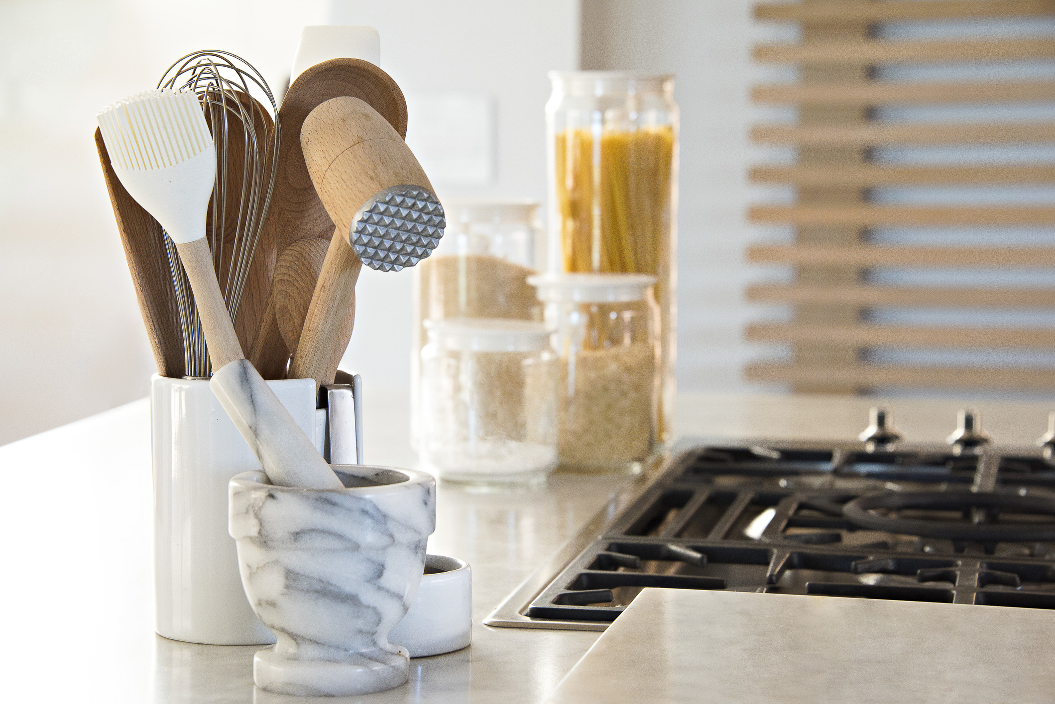 Container of wooden kitchen utensils right next to a stove.