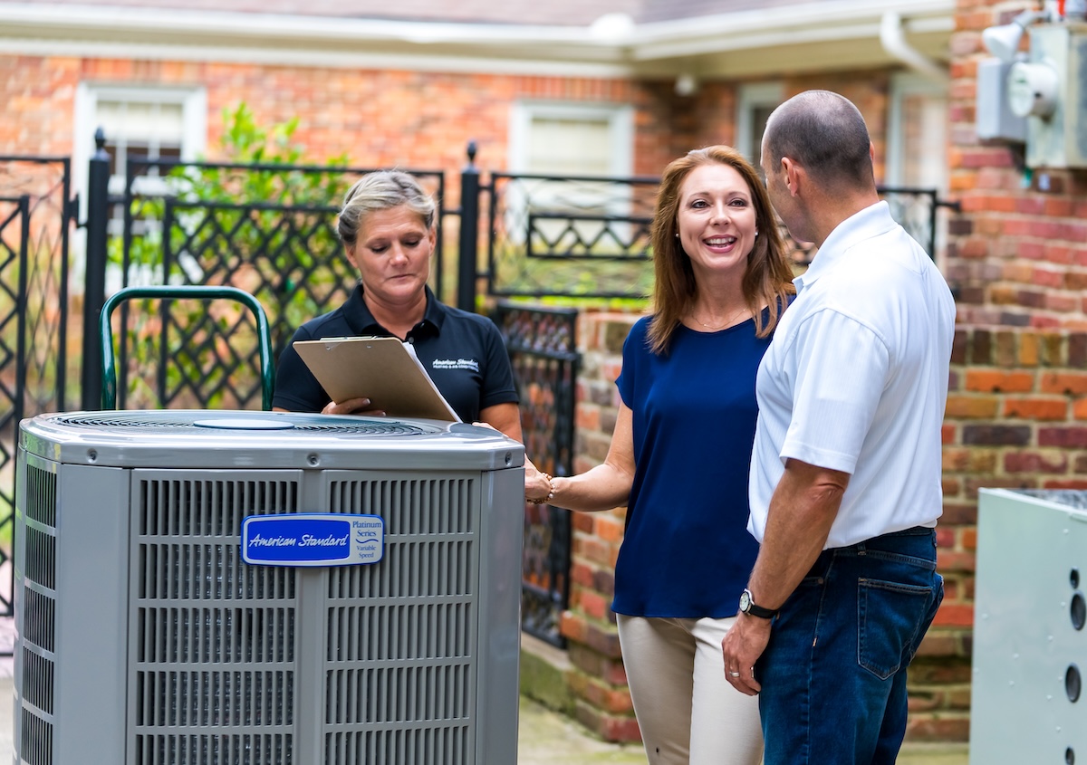 Homeowners working with an HVAC technician to install a new heat pump to heat and cool their home.