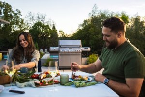 Two people enjoying grilled foods, cooked on a Monument Grills Eminence 605 grill
