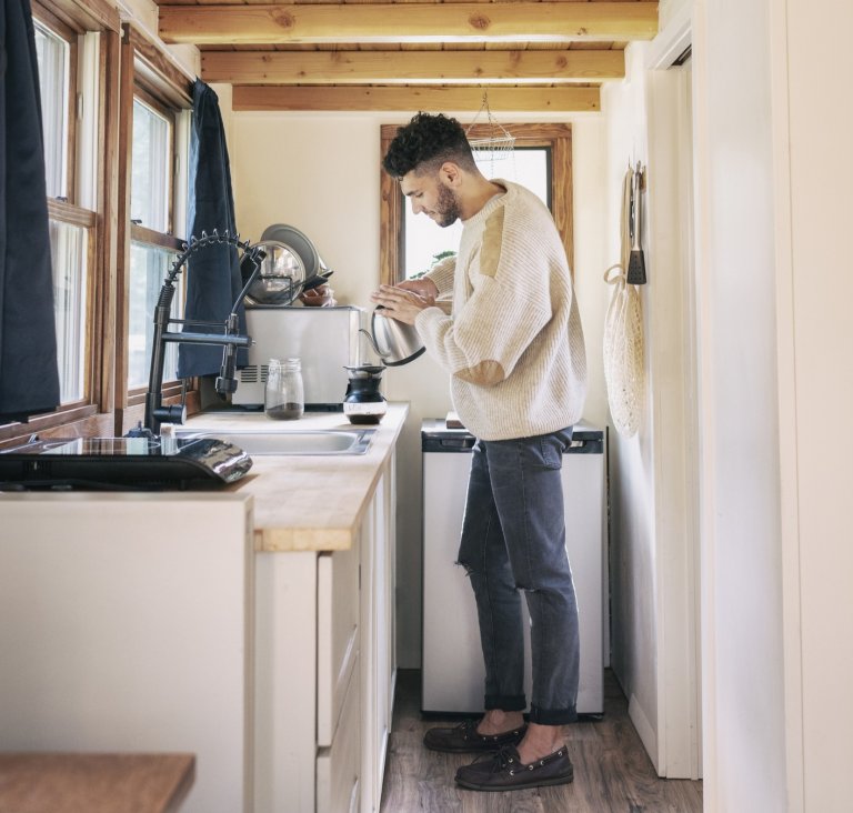 Young man making coffee in a tiny kitchen