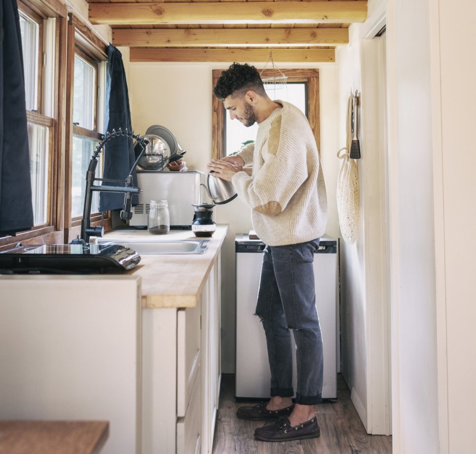 Young man making coffee in a tiny kitchen