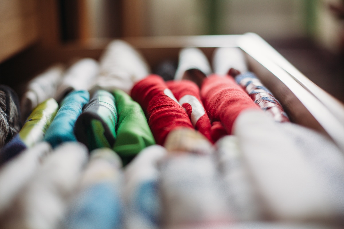 Folded T-shirts standing on end in a drawer.