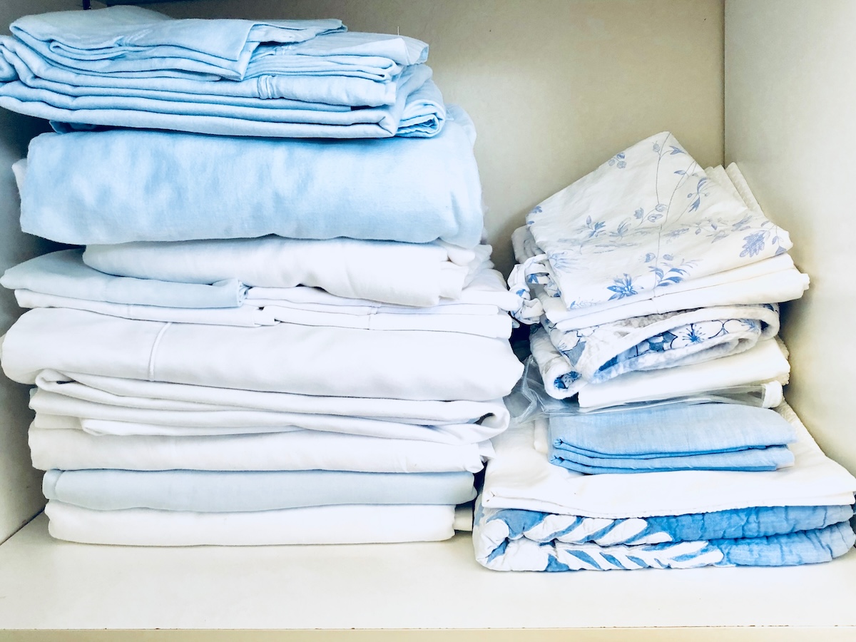 A set of blue linens folded neatly in a closet.