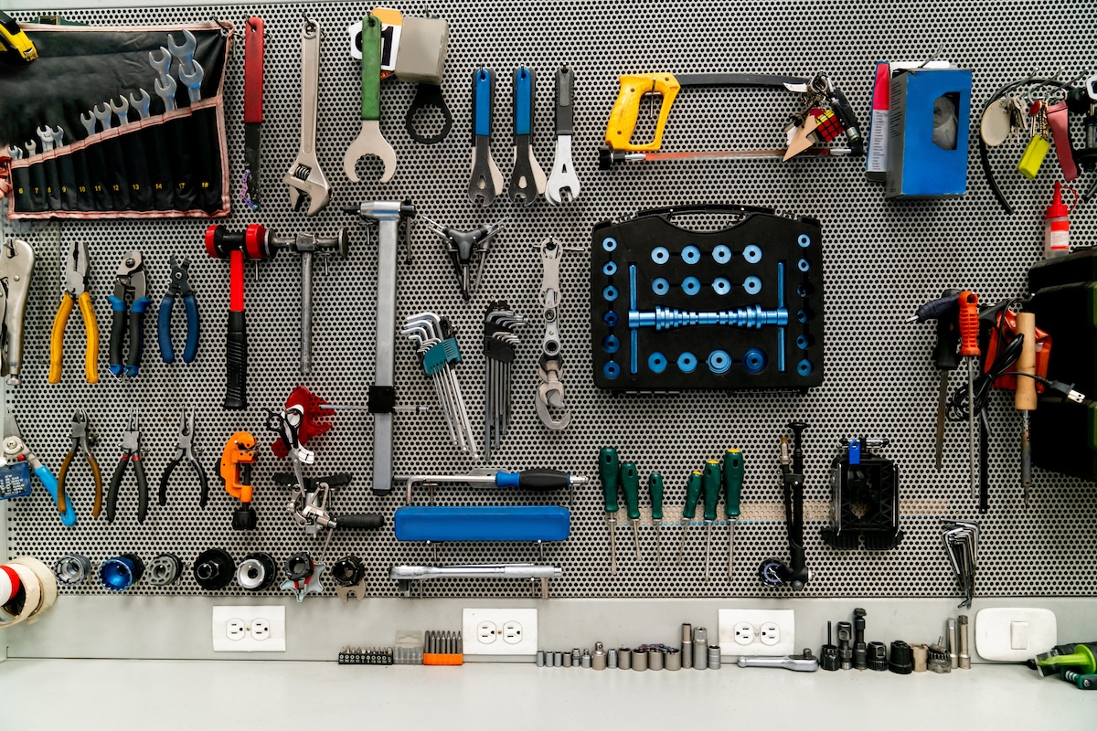 Tools hanging on a vertical wall in a garage.
