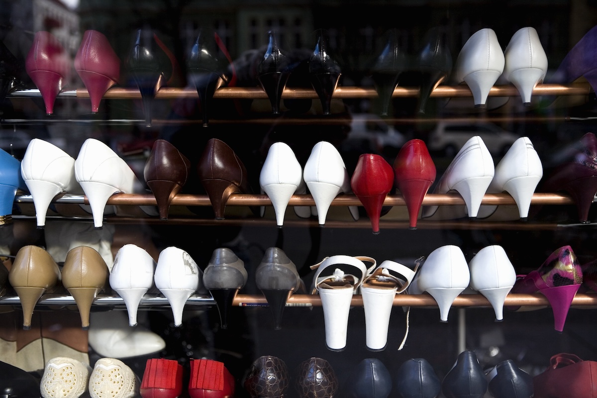 Several pairs of high heels hanging on a shoe rack with railings.