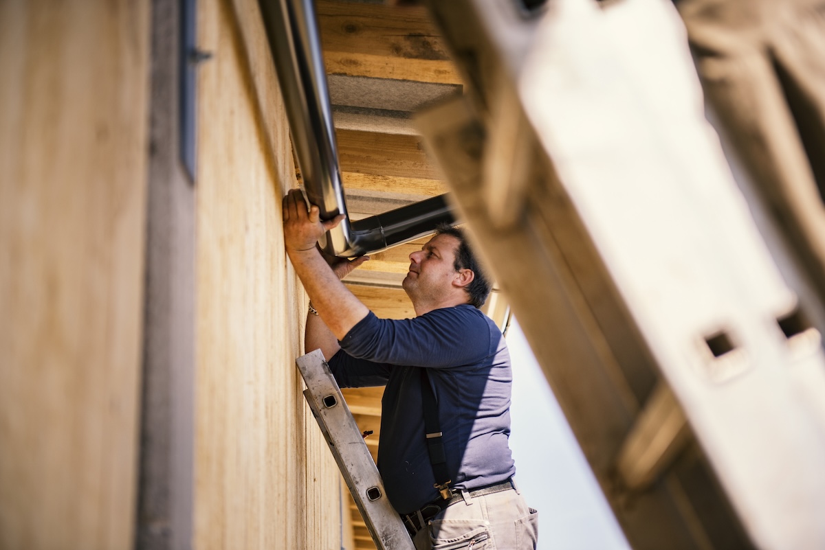 A man installs a rain gutter to the exterior of a home.