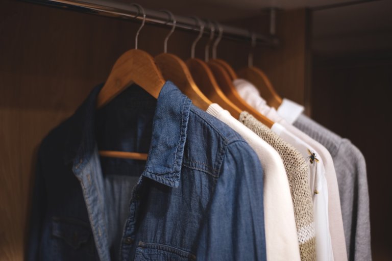 A set of matching clothes hanging next to each other in a closet.