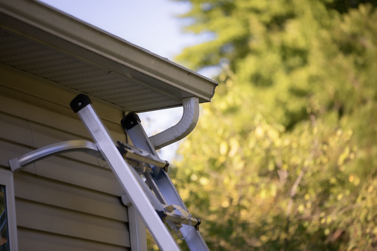 A ladder leaning against a home exterior for rain gutter maintenance.