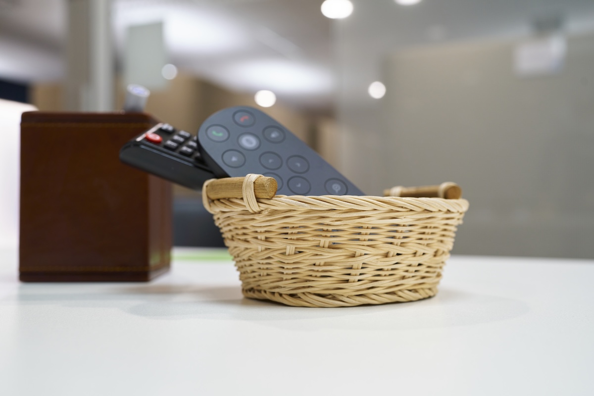 Remote control organized inside a basket on a table.