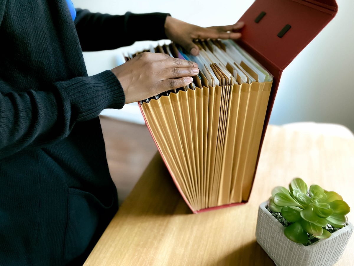 A woman searches through a large folder of instruction manuals.
