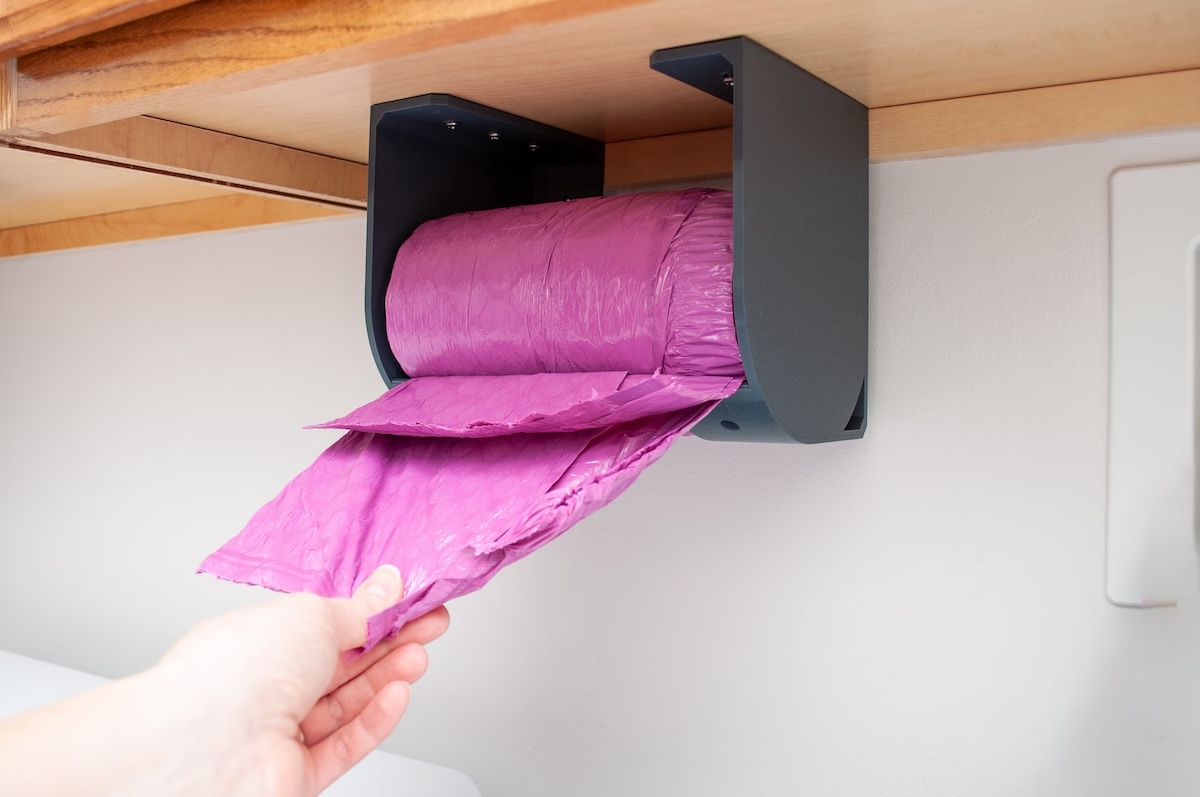 A roll of pink trash bags on a paper towel holder.