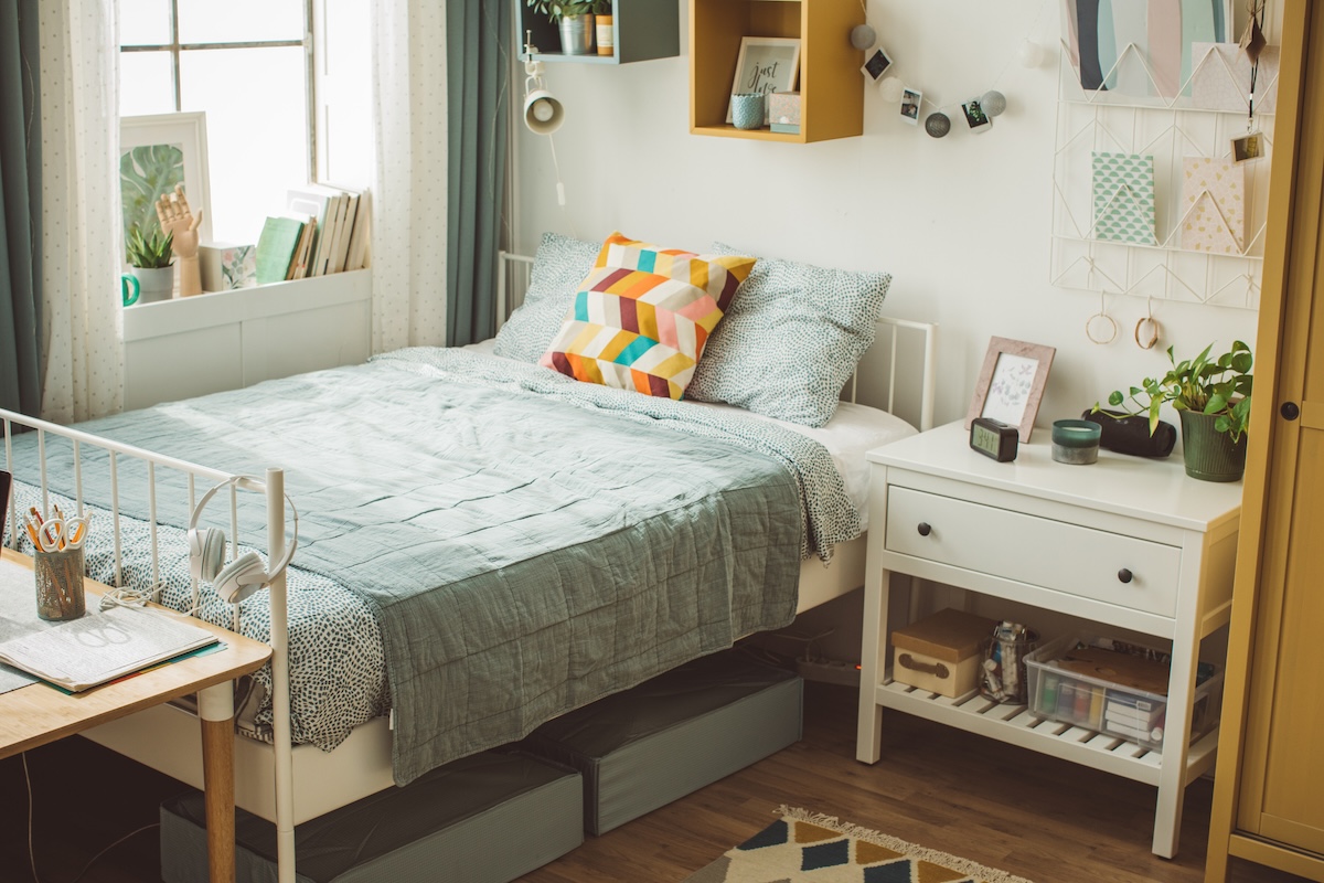 Storage bins under a bed with a blue bedspread.