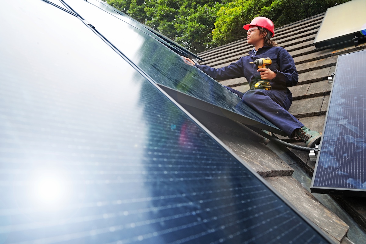 An engineer installing solar panels on a home roof.