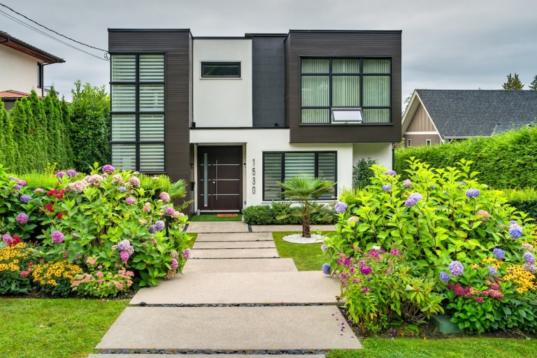 A modern house with colorful plants in the front for curb appeal.