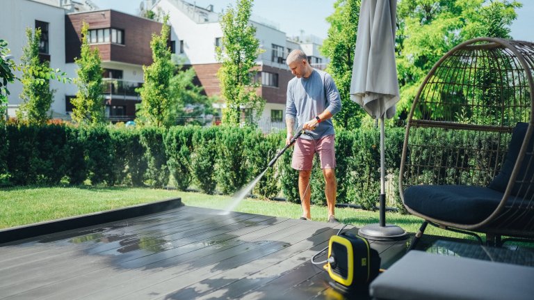 Mature man cleaning the patio decking with pressure washer