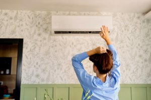 A homeowner feeling air coming from air conditioner during hot summer day.