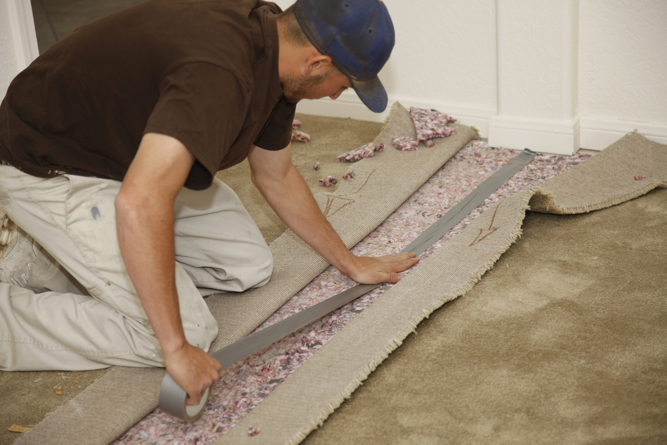 Young man on floor installing carpet.