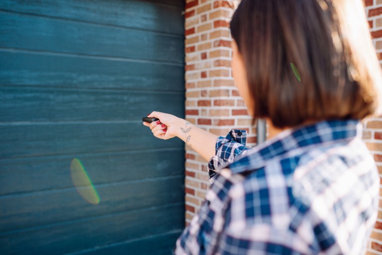 Woman holding and using remote control to open a garage door.