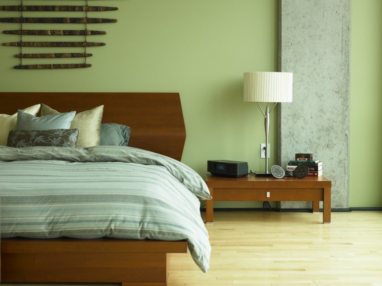 Bed and night table in bedroom that is all green.