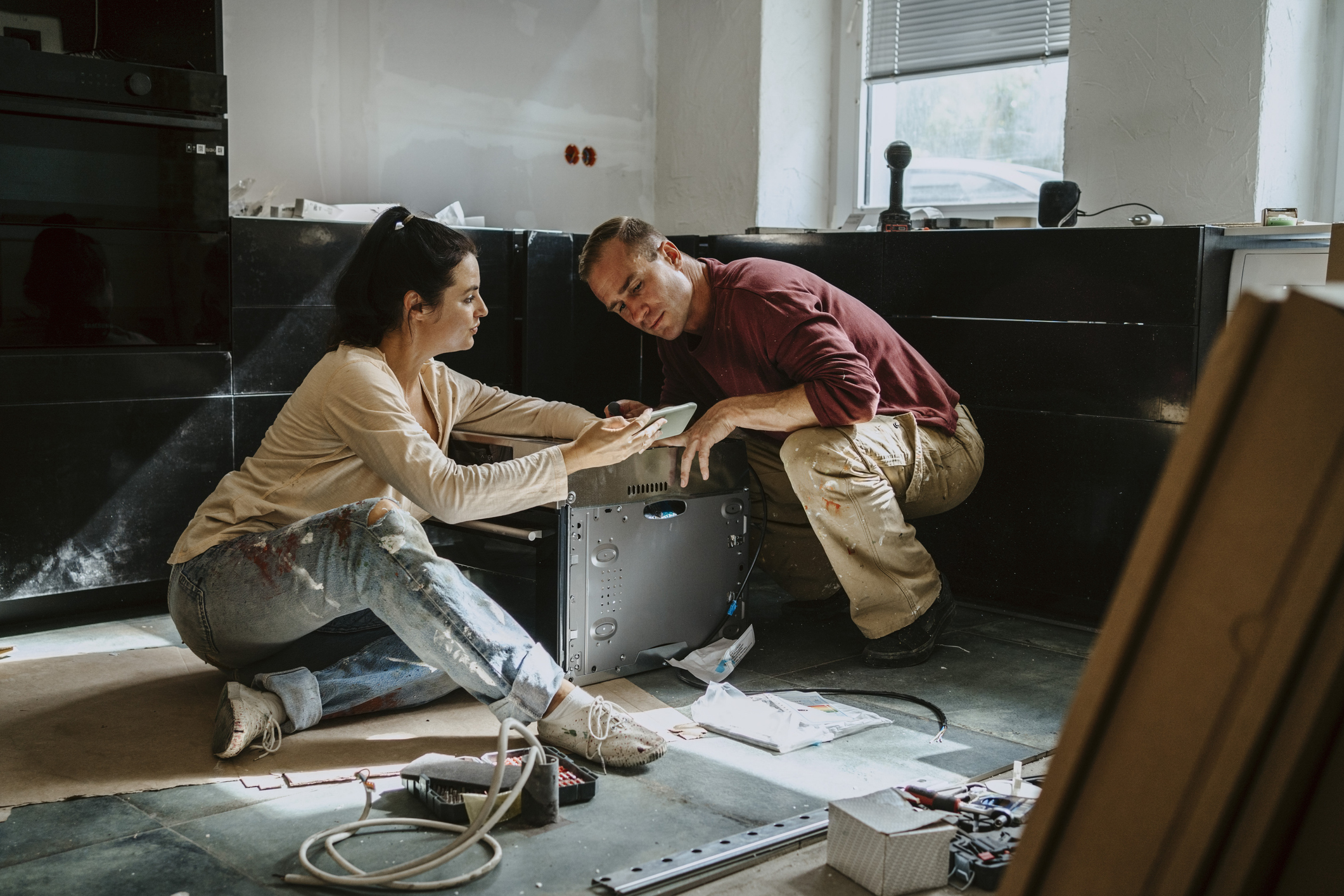 Couple installing kitchen appliance.