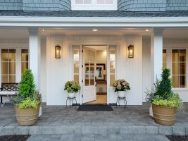 A white home with a porch decorated with planters.