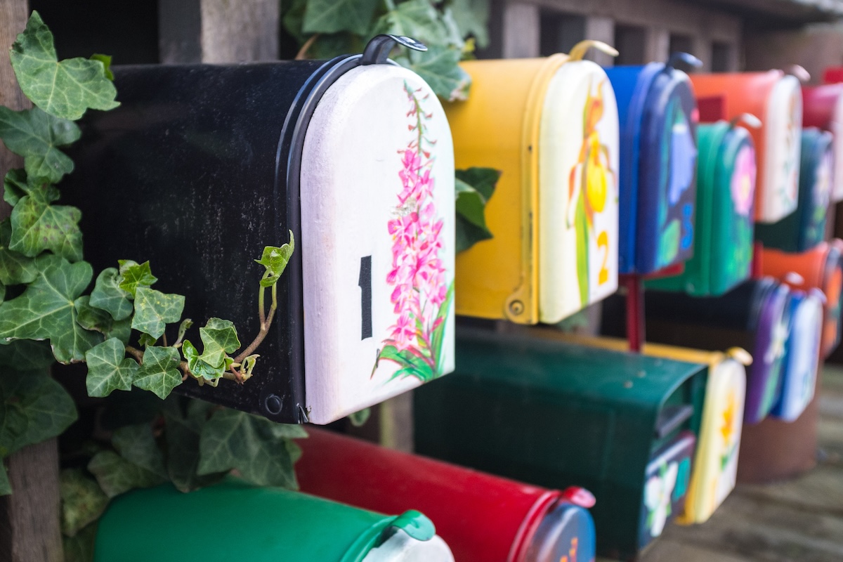 A row of mailboxes with colorful paintings of flowers on them.