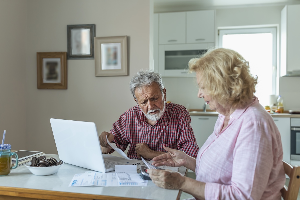 An older couple sits at the table and pays their utilities bills.