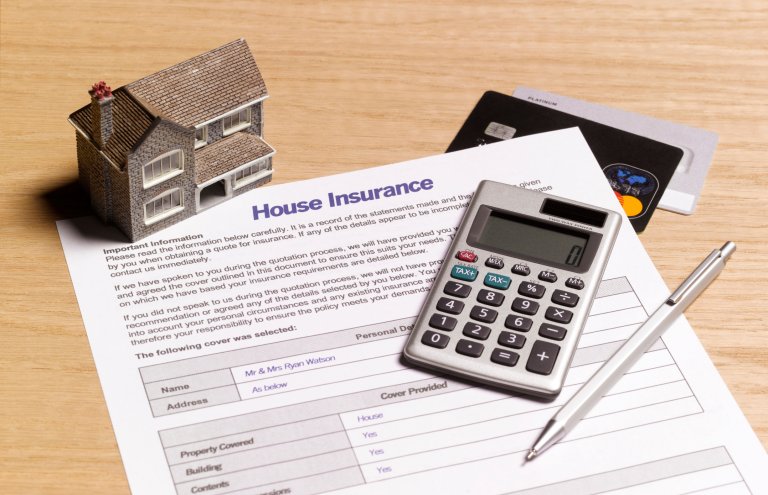 House insurance paperwork and calculator on a table.
