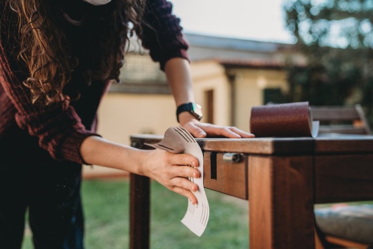 A person sanding a wood desk getting ready to refinish it.