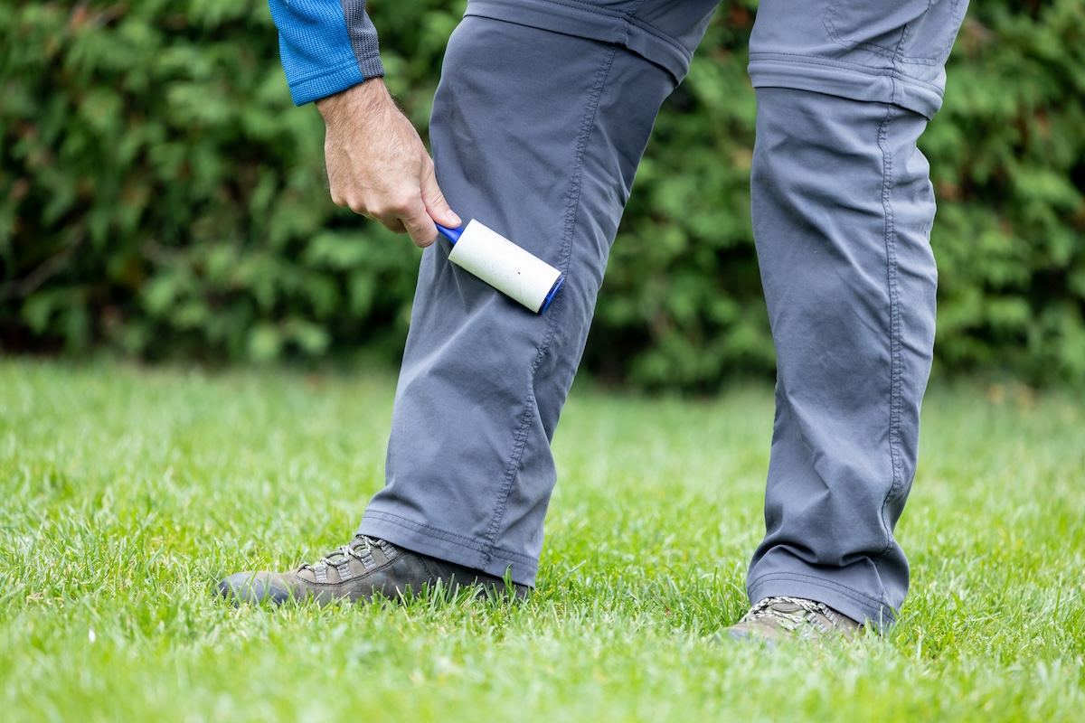 A person using a lint roller to pull ticks off of clothing after working in the garden.