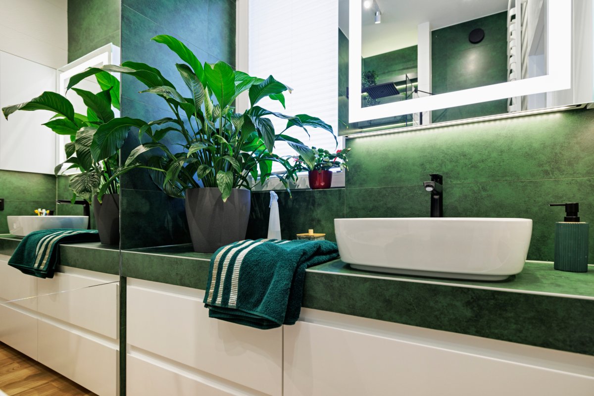 Bathroom with green and white tiles, black faucet. and white lacquer drawers.