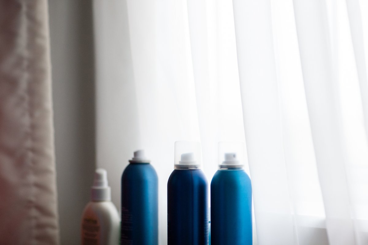 Hairspray cans sitting on a windowsill.