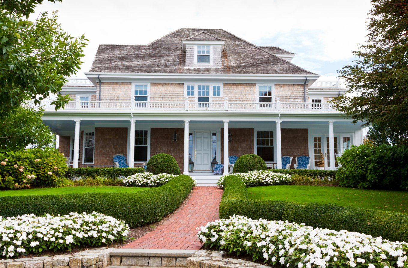 Beautifully landscaped front yard with flowers, lush grass and bushes is in foreground.